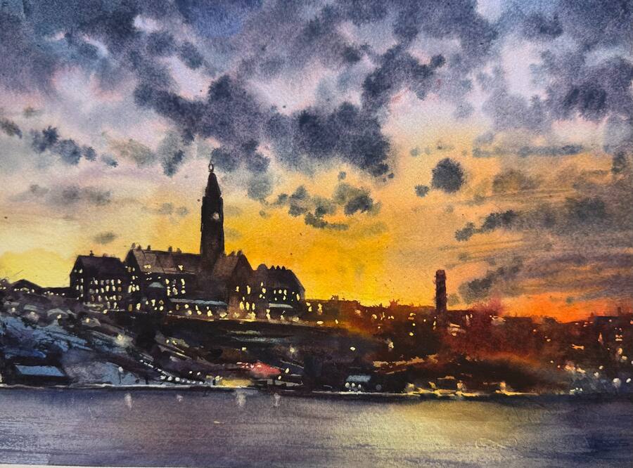 Stadsvy över Danviken i skymning med mörka moln och upplyst torn.