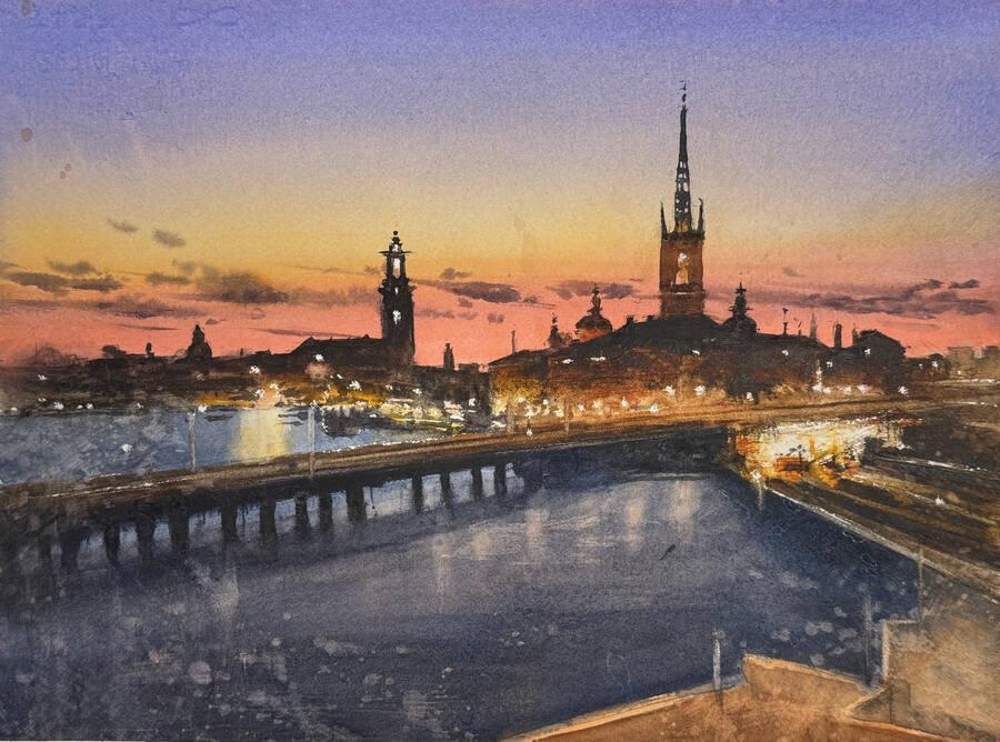 Stockholms skyline i sommarskymning med bro och kyrktorn.